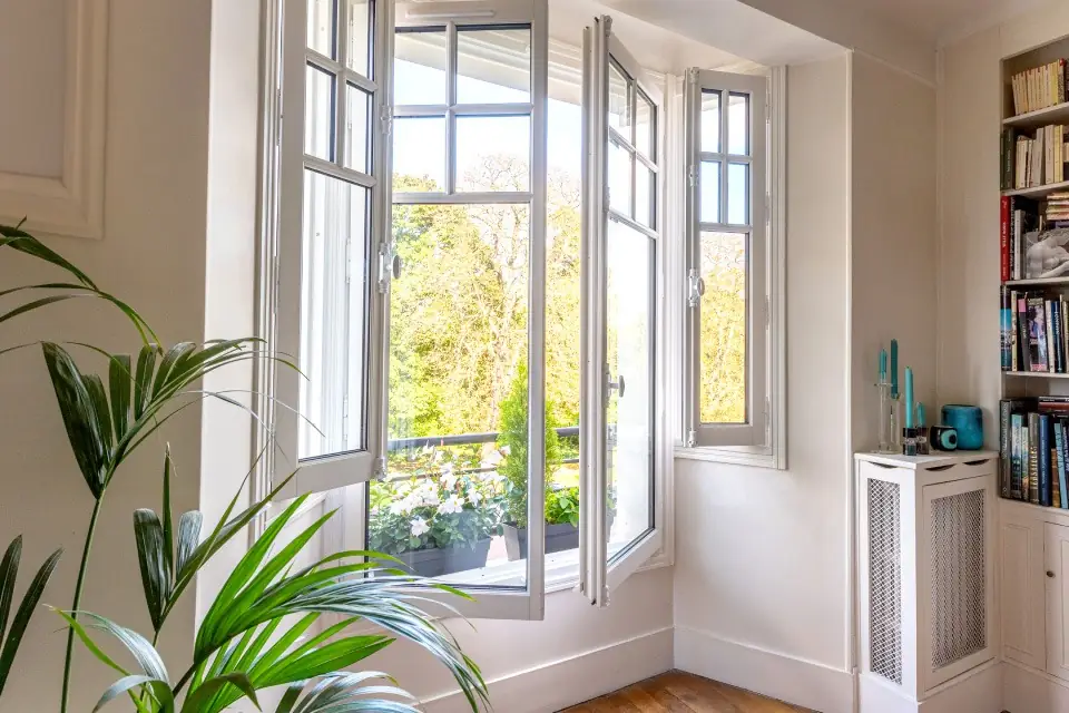 Une grande fenêtre avec des volets en bois dans un appartement bourgeois élégamment décoré.